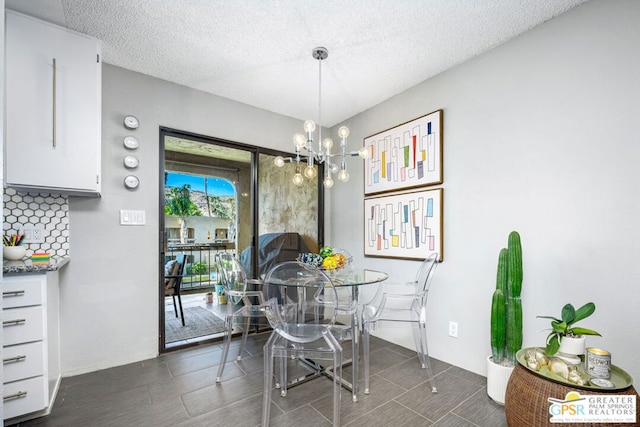 dining space featuring dark tile patterned floors, a chandelier, and a textured ceiling