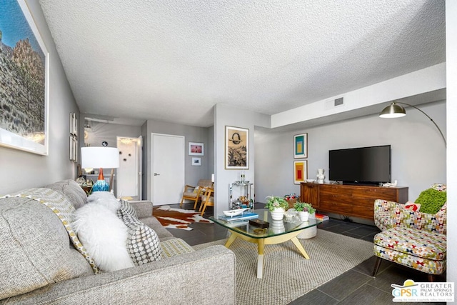 living room featuring dark tile patterned flooring and a textured ceiling