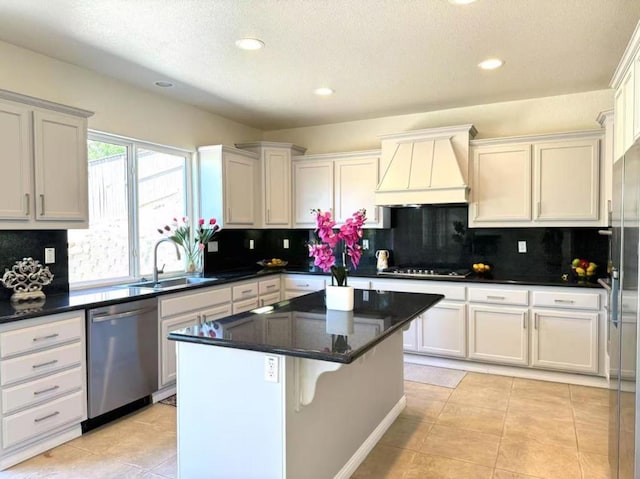 kitchen with custom exhaust hood, a center island, light tile patterned floors, sink, and stainless steel appliances