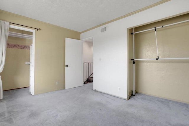 unfurnished bedroom with light carpet, a closet, ornamental molding, and a textured ceiling