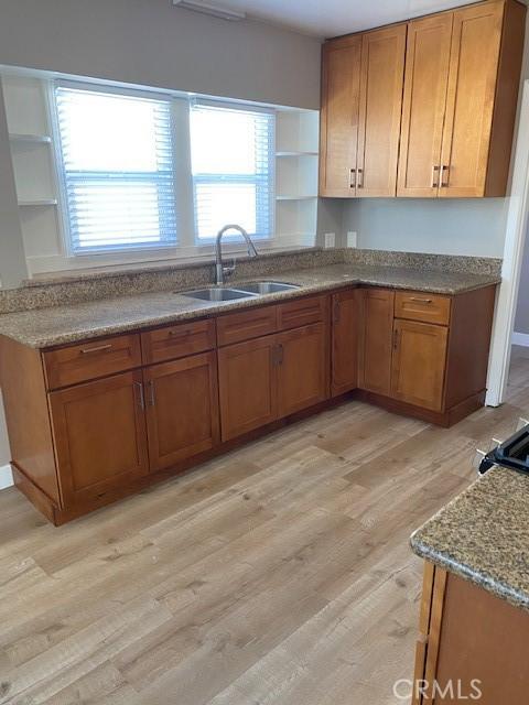 kitchen featuring light stone counters, sink, and light hardwood / wood-style flooring