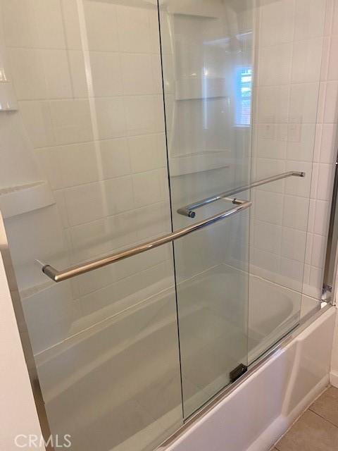 bathroom featuring tile patterned floors and bath / shower combo with glass door