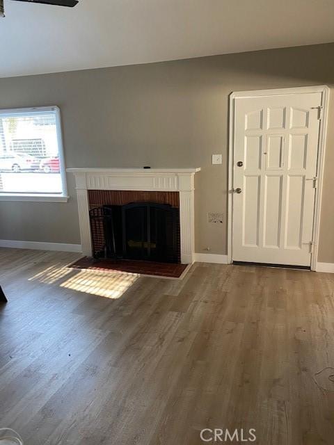 unfurnished living room with hardwood / wood-style flooring and a brick fireplace