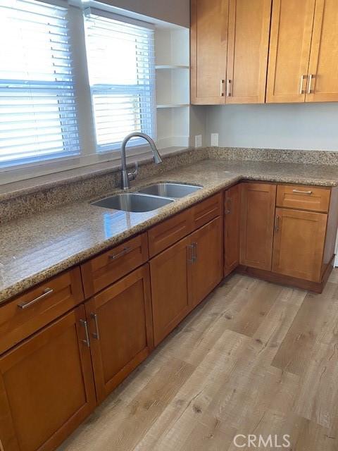 kitchen with light stone counters, sink, and light hardwood / wood-style flooring