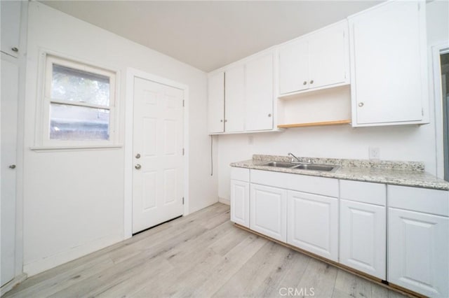 kitchen with white cabinetry, sink, and light wood-type flooring