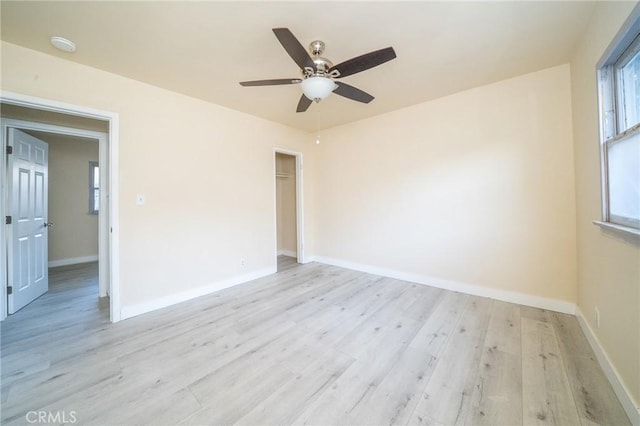 empty room with ceiling fan, light hardwood / wood-style floors, and a healthy amount of sunlight