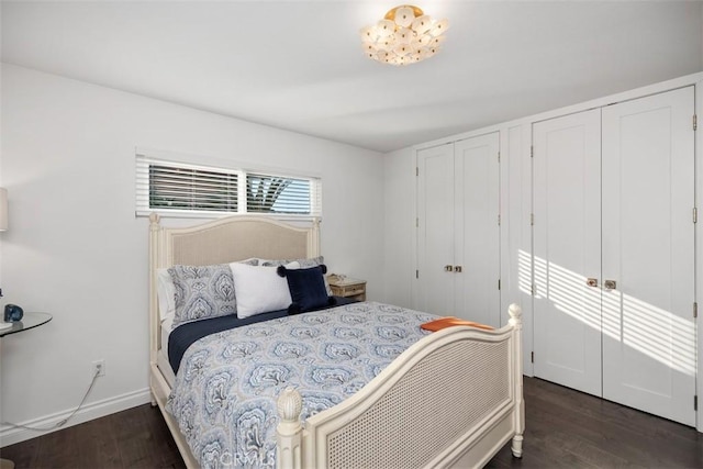 bedroom with wood finished floors, two closets, and baseboards