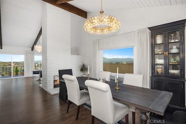 dining space with a chandelier, a brick fireplace, lofted ceiling with beams, and wood finished floors