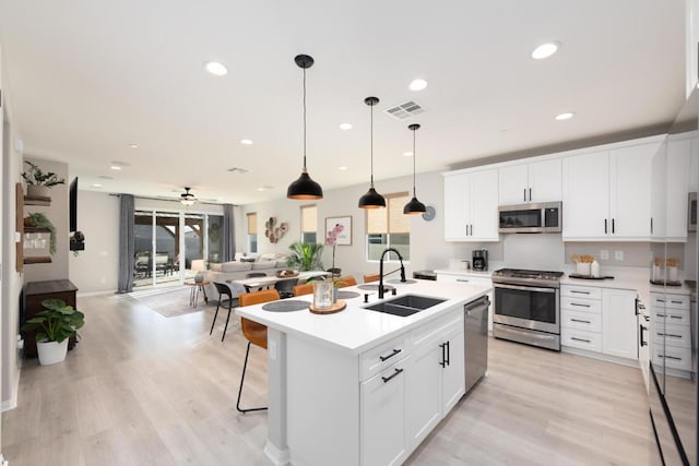 kitchen featuring appliances with stainless steel finishes, white cabinetry, a center island with sink, and sink