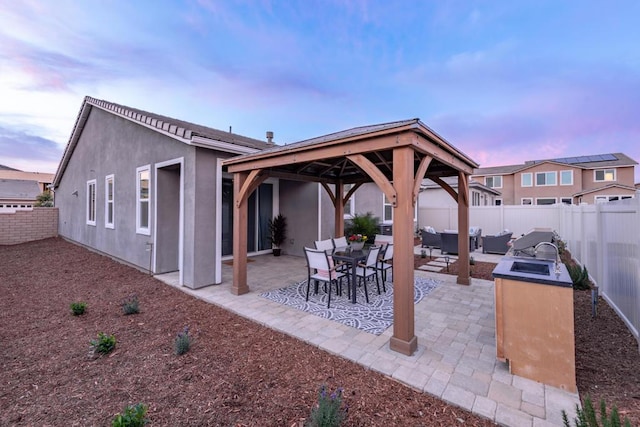 patio terrace at dusk featuring a gazebo and area for grilling