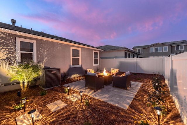 patio terrace at dusk featuring central AC and a fire pit