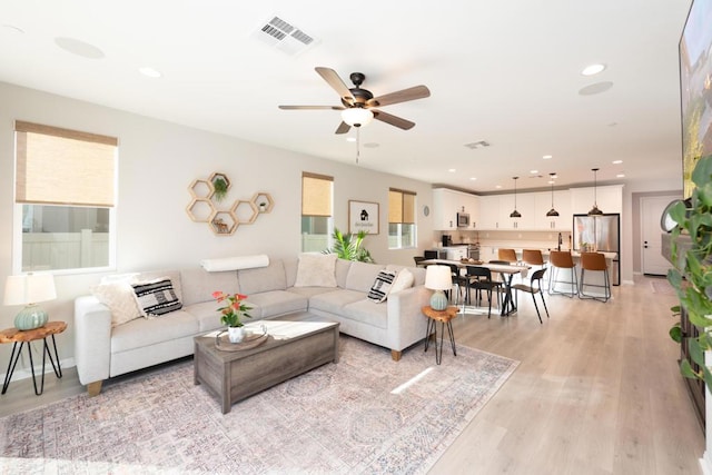 living room featuring light wood-type flooring and ceiling fan