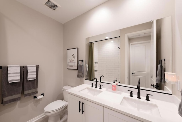 bathroom featuring a tile shower, vanity, and toilet