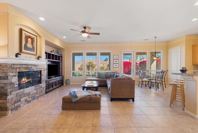 living room with ceiling fan, light tile patterned floors, built in features, and a fireplace