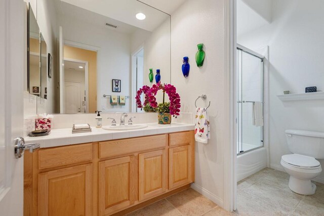 full bathroom featuring toilet, vanity, tile patterned flooring, and shower / bath combination with glass door