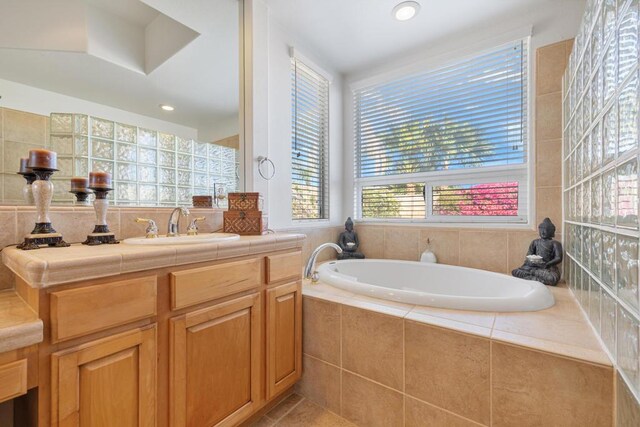 bathroom with tiled bath, tile patterned floors, and vanity