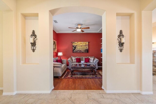 living room featuring ceiling fan, ornamental molding, and wood-type flooring