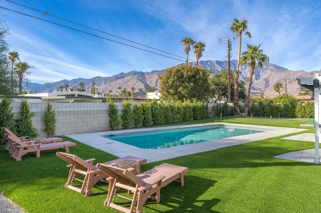 view of swimming pool featuring a lawn and a mountain view