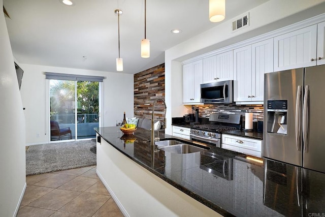 kitchen with tasteful backsplash, white cabinets, decorative light fixtures, and appliances with stainless steel finishes