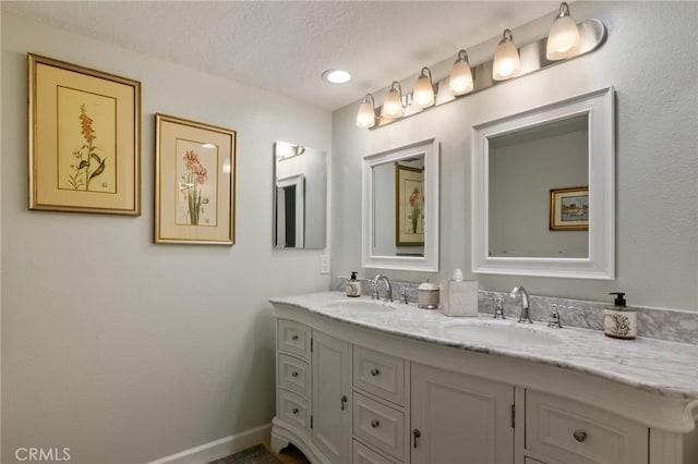 bathroom featuring double vanity, a sink, and baseboards