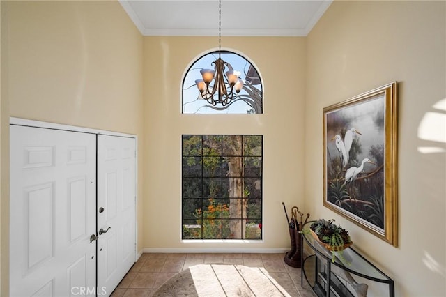 foyer entrance featuring a healthy amount of sunlight, tile patterned flooring, ornamental molding, and a notable chandelier