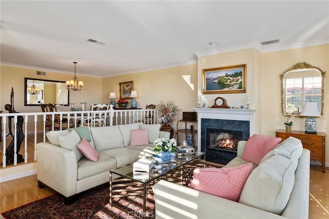 living room with a fireplace, a chandelier, hardwood / wood-style flooring, and crown molding