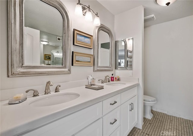 full bath with visible vents, double vanity, a sink, and toilet