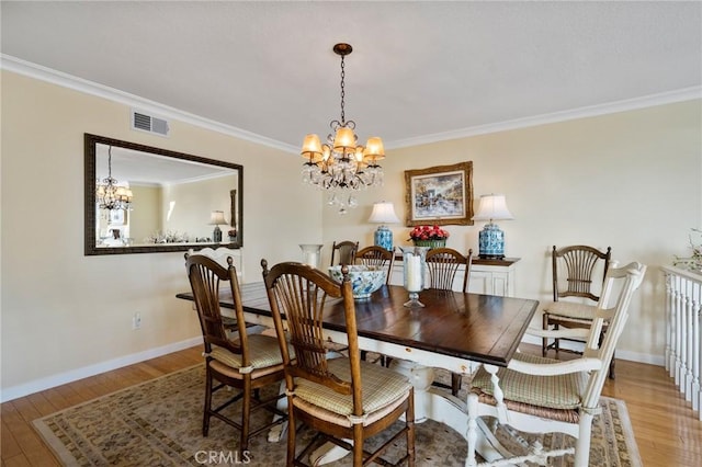 dining area with an inviting chandelier, ornamental molding, and light hardwood / wood-style flooring