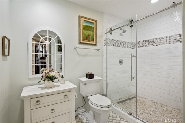 bathroom featuring toilet, a shower with shower door, and vanity