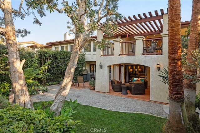 back of house with a balcony, a patio area, a pergola, and stucco siding