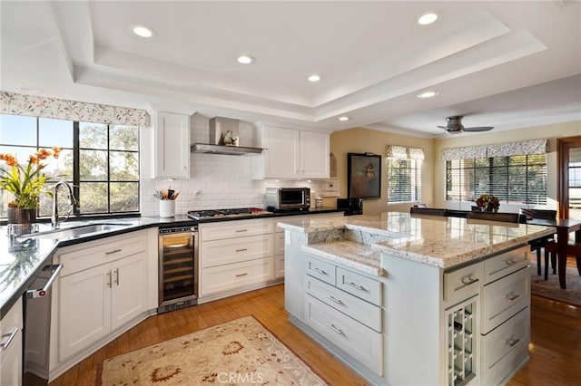 kitchen featuring white cabinetry, beverage cooler, a tray ceiling, and sink