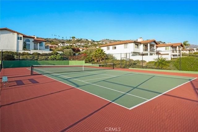 view of tennis court featuring fence and a residential view