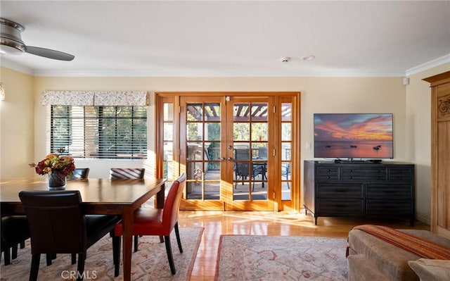 dining space featuring a ceiling fan, french doors, crown molding, and wood finished floors