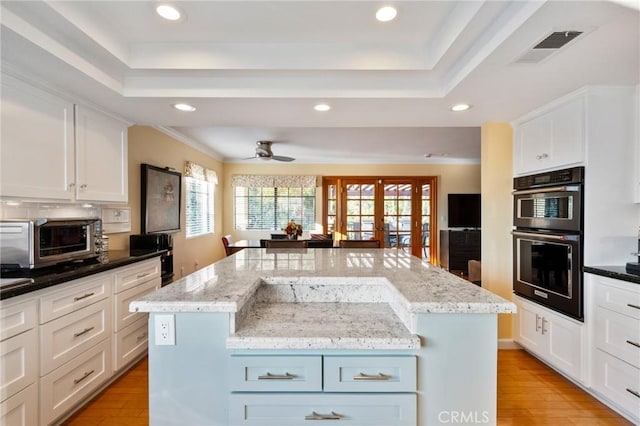 kitchen with a center island, a raised ceiling, visible vents, and dobule oven black