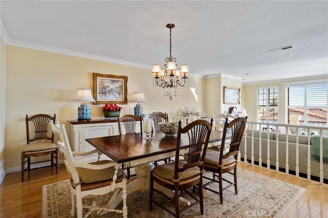 dining room featuring an inviting chandelier, ornamental molding, and light hardwood / wood-style flooring