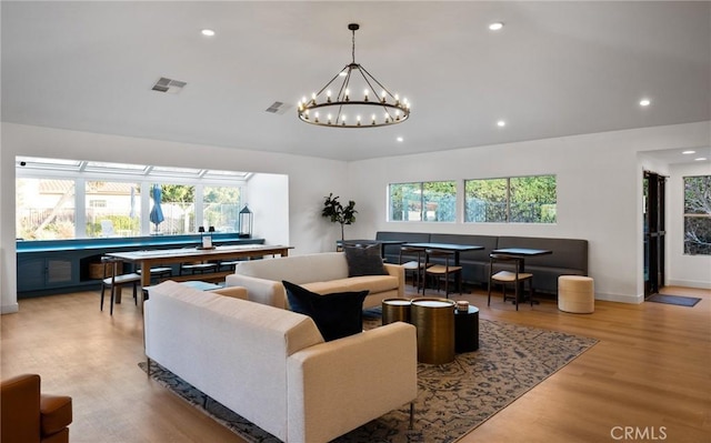 living room featuring a chandelier, light hardwood / wood-style floors, and a wealth of natural light