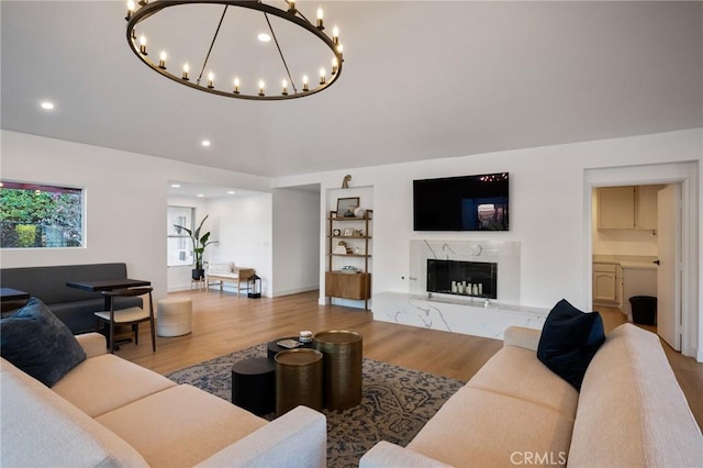 living room featuring a premium fireplace, wood finished floors, and recessed lighting