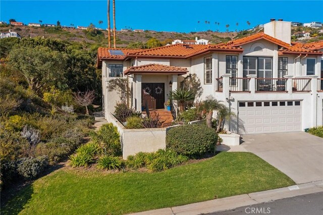 mediterranean / spanish home featuring a balcony, a front yard, and a garage