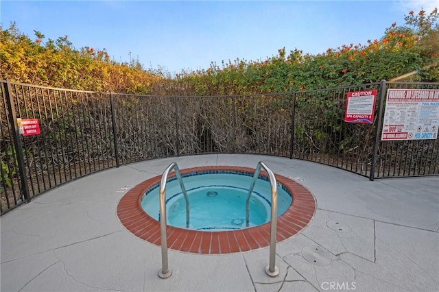 view of swimming pool with fence and a hot tub