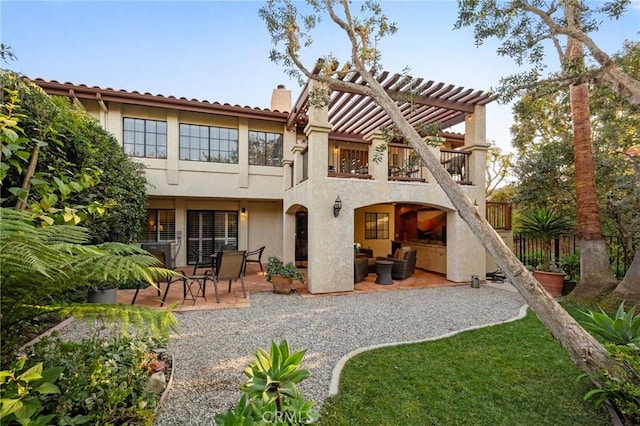 back of property with a balcony, stucco siding, a pergola, a chimney, and a patio area