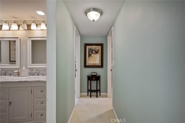 hall with sink and light colored carpet