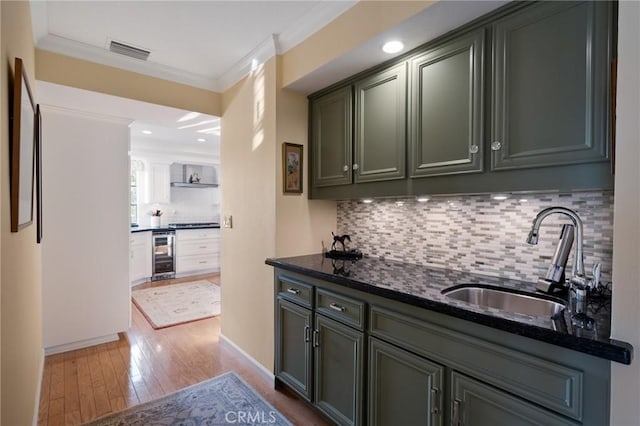 bar with visible vents, wine cooler, ornamental molding, wood finished floors, and a sink