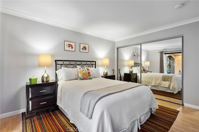 bedroom featuring baseboards, wood finished floors, and crown molding