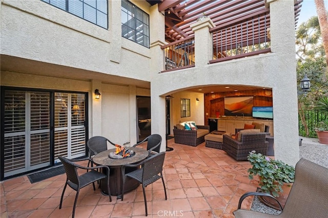 view of patio with an outdoor living space with a fire pit and a balcony