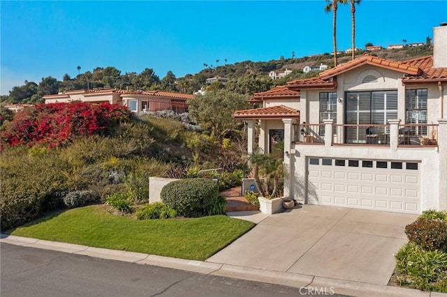 mediterranean / spanish-style house featuring a balcony, a front lawn, and a garage