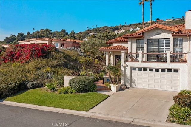 view of front of property featuring a balcony, driveway, a tile roof, and stucco siding