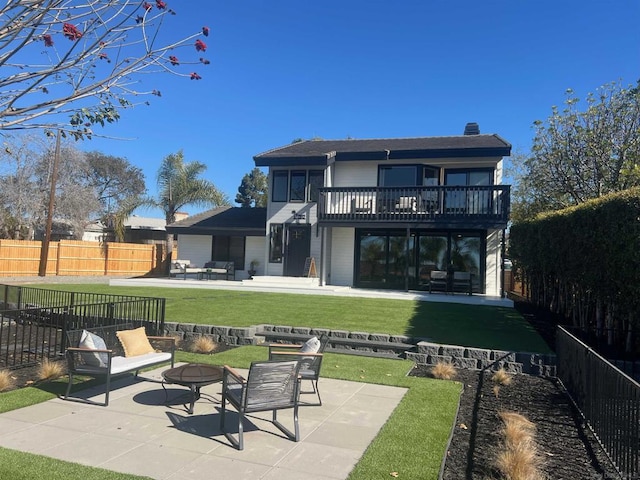 rear view of house featuring a balcony, a patio area, a yard, and an outdoor living space with a fire pit