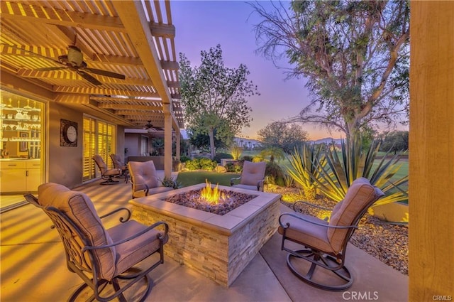 patio terrace at dusk with a ceiling fan, an outdoor fire pit, and a pergola