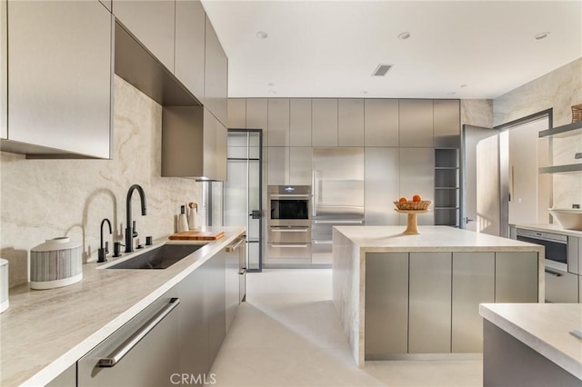 kitchen featuring decorative backsplash, appliances with stainless steel finishes, gray cabinets, and sink