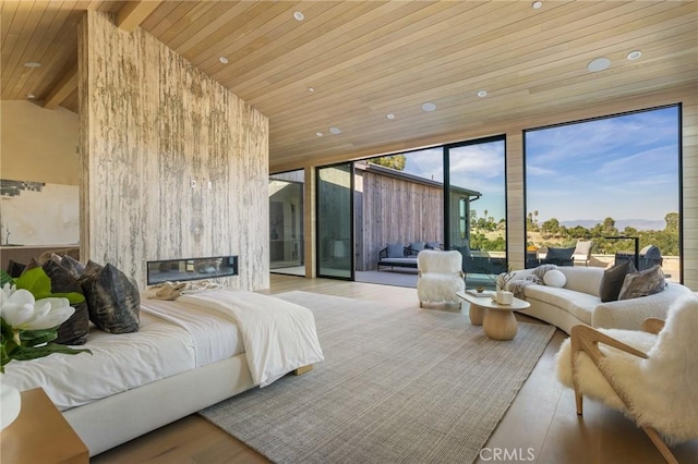 bedroom featuring wooden ceiling, light hardwood / wood-style flooring, vaulted ceiling with beams, access to exterior, and a large fireplace